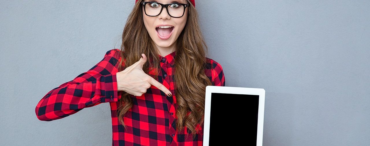 A woman holding up an ipad with one hand and pointing to the other.