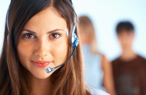 Call Center Operator Young beautiful woman with headset with some people at the background